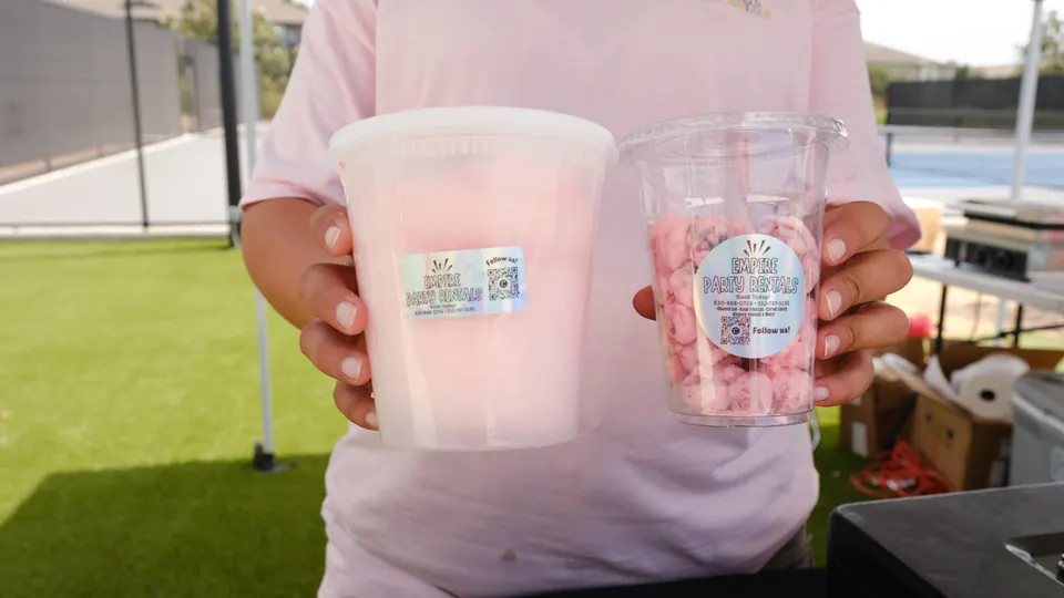 A vendor holding pink cotton candy and sweet treats